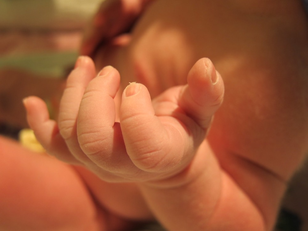 Klein handje van een pasgeboren baby in warm licht